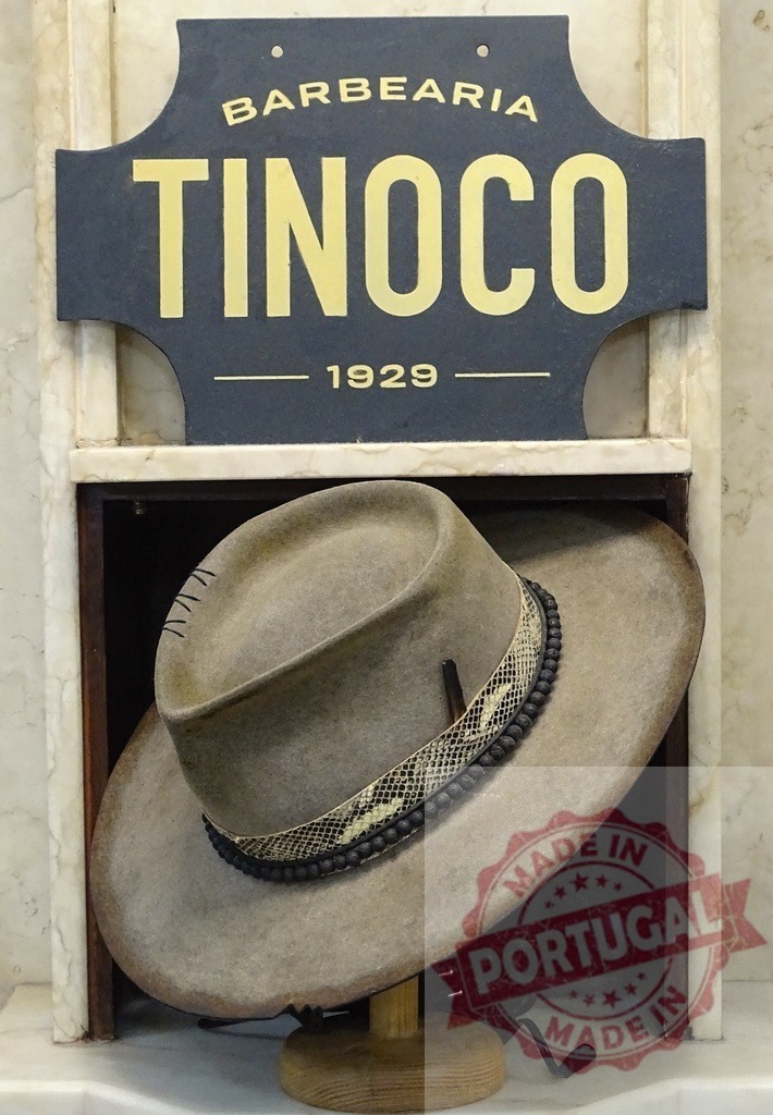 Barbearia Tinoco 1929 displaying classic vintage fedora hat | Barbearia Tinoco sign with a vintage fedora hat in a display cabinet, showing heritage and style - Realisiert mit Pictrs.com