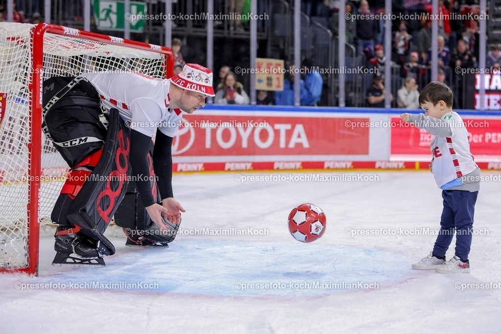 KEC03012501062 | 03.01.2025, Eishockey, Penny DEL, Kölner Haie - EHC Red Bull München, Spieltag 33, Lanxess-Arena Köln: Abschlussjubel nach dem 3:2 Sieg für die Kölner Haie. Julius Hudacek (Kölner Haie #35) feiert den Sieg in einem Trickot vom Fußballverein 1.FC Köln und spielt mit seinem Sohn eine Runde Fußball auf dem Eis.