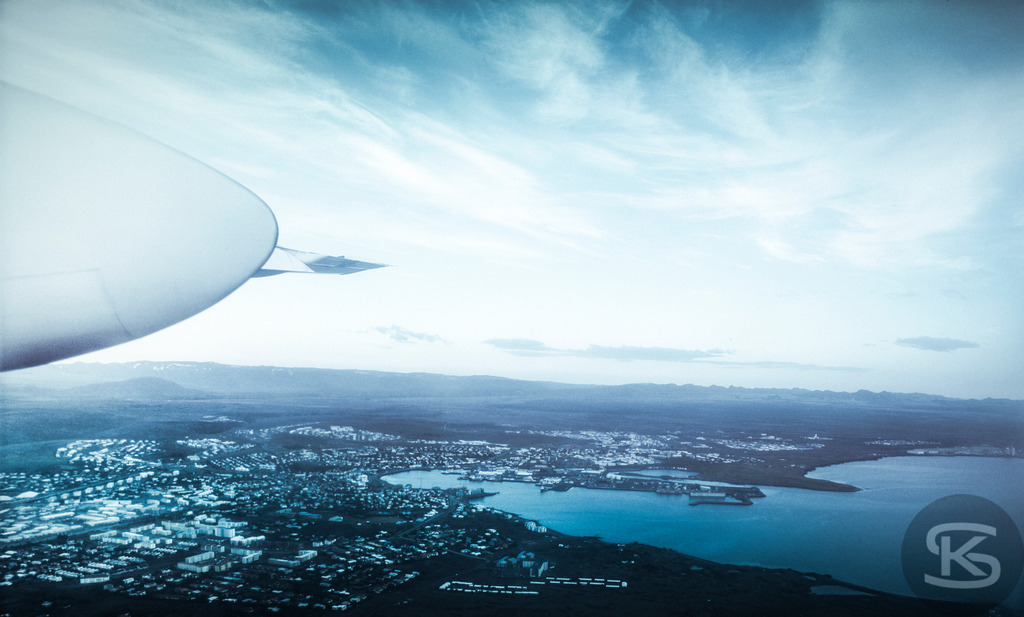 Blick auf Reykjavik aus dem Flugzeug bei der Landung | Ein faszinierender Luftbildblick auf die isländische Hauptstadt Reykjavik und die umliegende Küstenlandschaft, aufgenommen aus dem Flugzeugfenster während des Landeanflugs. Das Bild fängt die einzigartige Topographie der Stadt mit ihrer Lage am Meer und vor einer Bergkulisse ein und vermittelt die Atmosphäre der Ankunft in Island. - Realisiert mit Pictrs.com