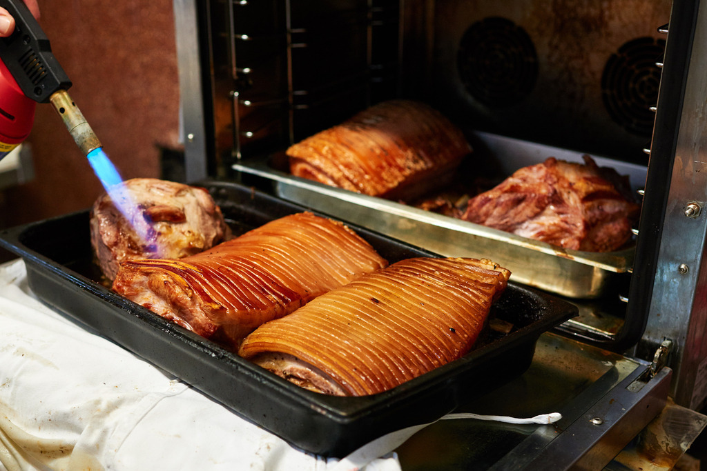 Fleischerei Dormayer | Langenzersdorf, Austria - February 12, 2019: Fleischerei Dormayer; mit einem Bunsenbrenner wird die Kruste beim Schweinsbraten gemacht. - Realisiert mit Pictrs.com