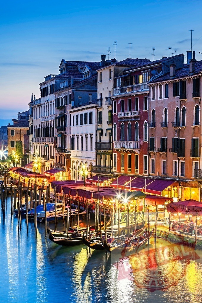 Gondolas moored along Grand Canal buildings at dusk | Venice Grand Canal cityscape with illuminated buildings and moored gondolas reflecting in water - Realized with Pictrs.com