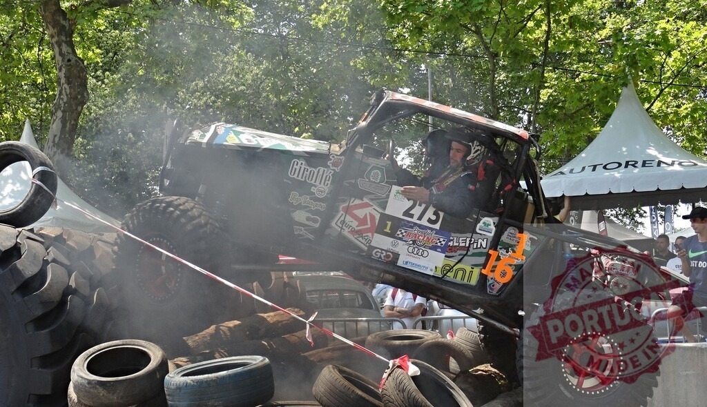 Pilot driving offroad vehicle climbing tires obstacle during competition | Offroad vehicle climbing a difficult obstacle made of tires during an auto competition with pilot driving - Realized with Pictrs.com