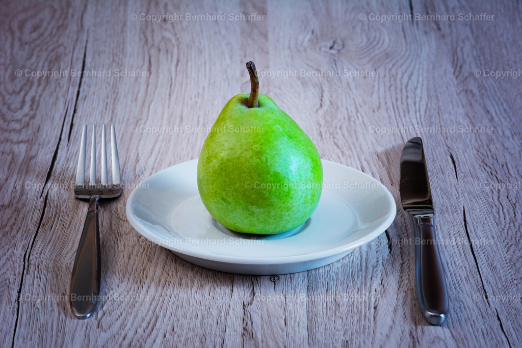 Birne auf Teller | Eine Birne liegt auf einem Teller und Besteck. - Realisiert mit Pictrs.com