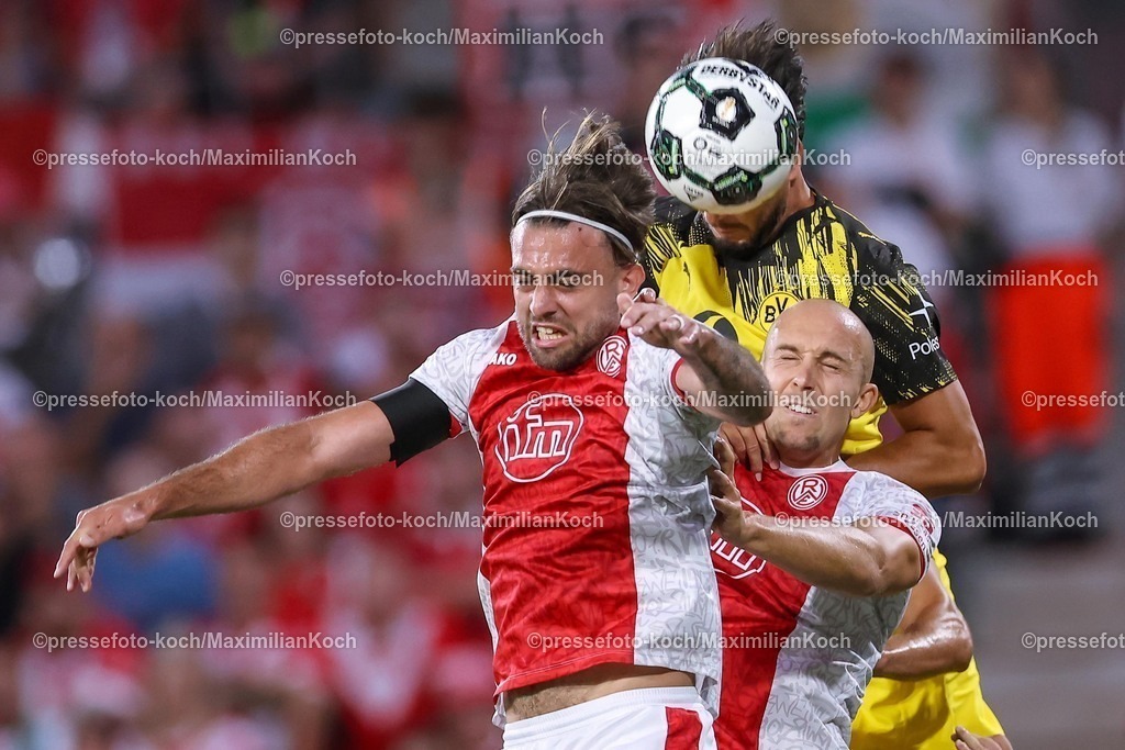 DFB18082501043 | 2025.08.18, Fußball, 1.Runde DFB-Pokal, Rot-Weiss Essen - Borussia Dortmund, Stadion Hafenstraße, Saison 2025 2026: Jose Enrique Rios Alonso&nbsp;(Rot-Weiss Essen #23) Tobias Kraulich&nbsp;(Rot-Weiss Essen #33) gegen Ramy Bensebaini&nbsp;(BVB #05) Kopfball Strafraumaltion Kopfballduell  DFB regulations prohibit any use of photographs as image sequences and or quasi-video.