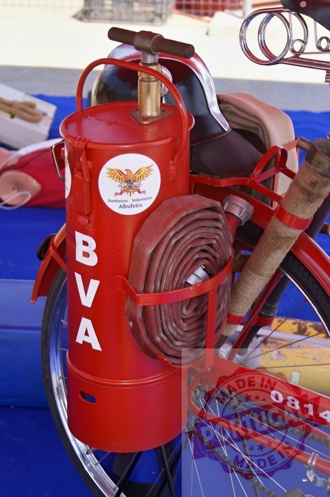 Red vintage firefighter bicycle with equipment, hose, and helmet | Vintage firefighter bicycle from Bombeiros Voluntários Albufeira - Realized with Pictrs.com