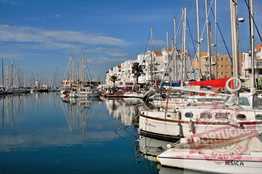 Marina with sailboats and yachts reflecting in calm water | Marina full of yachts and boats moored in still waters, showing building reflections - Realized with Pictrs.com