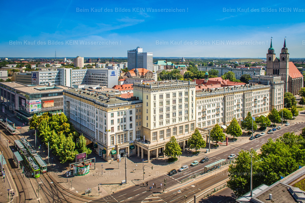 Magdeburg Breiter Weg Mc Donalds-8454 | Blick aus der Vogelperspektive auf den Breiten Weg im Zentrum von Magdeburg. Im Vordergrund erstreckt sich die breite Straße mit ihren Straßenbahngleisen, Haltestellen und den angrenzenden Gebäuden. Im Mittelpunkt steht der langgestreckte Gebäudekomplex am früheren Standort der Gaststätte „Stadt Prag“. Heute befinden sich hier unter anderem gastronomische Angebote wie McDonald’s und das Café Flair. Im Hintergrund sind die Türme der Johanniskirche zu erkennen, die die Silhouette der Innenstadt mitprägen. –  – Der Breite Weg zählt zu den traditionsreichsten Straßen Magdeburgs. Zu DDR-Zeiten war die Gaststätte Stadt Prag ein bekannter Treffpunkt und gehörte zum gesellschaftlichen Leben der Innenstadt. Gaststätten waren damals nicht nur Orte zum Essen und Trinken, sondern auch Treffpunkte für Familien, Feiern und Begegnungen. Mit der Wiedervereinigung veränderten sich die Nutzung und das Erscheinungsbild vieler Gebäude entlang der Straße. –  – Die Aufnahme zeigt, wie sich das Stadtzentrum im Laufe der Zeit gewandelt hat. Historische Bauwerke, Geschäftshäuser, Straßenbahnverkehr und moderne Gastronomie liegen dicht beieinander. Die Johanniskirche bildet dabei einen markanten Orientierungspunkt im Stadtbild. Aus der Luft wird deutlich, wie der Breite Weg als wichtige Verkehrs- und Geschäftsachse die verschiedenen Bereiche der Magdeburger Innenstadt verbindet. –  – Das Luftbild vermittelt einen Überblick über einen Teil der Magdeburger City, in dem sich Stadtgeschichte und heutiger Alltag begegnen. Es zeigt die Innenstadt nicht nur mit ihren bekannten Bauwerken, sondern auch mit den Straßen, Gebäuden und Orten, die das tägliche Leben in Magdeburg prägen. - Realisiert mit Pictrs.com