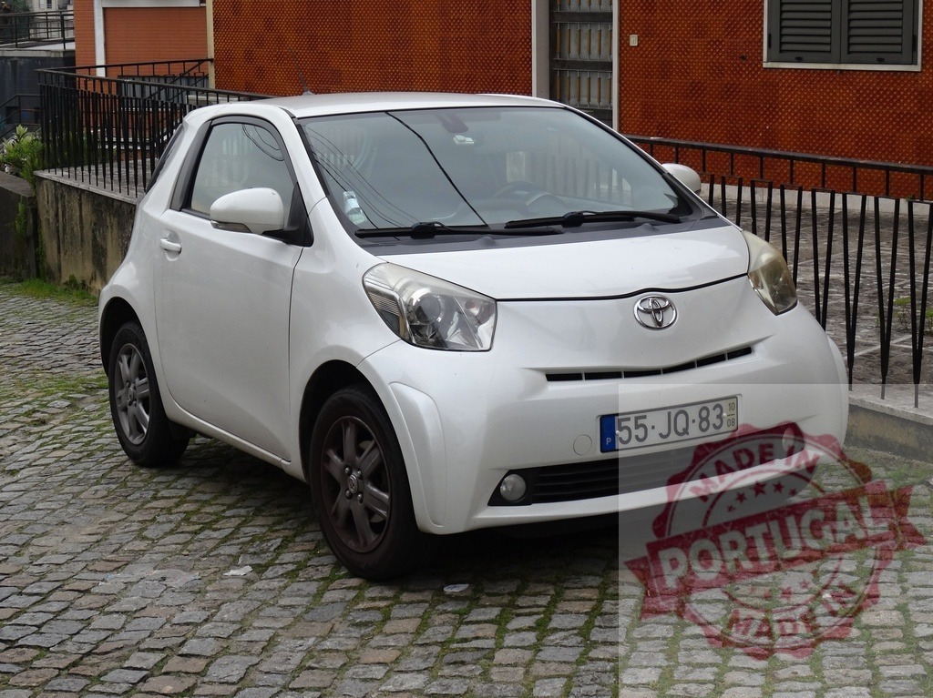 Toyota iQ compact city car parked on cobblestones | White Toyota iQ compact car parked on a cobblestone street in daylight - Realized with Pictrs.com