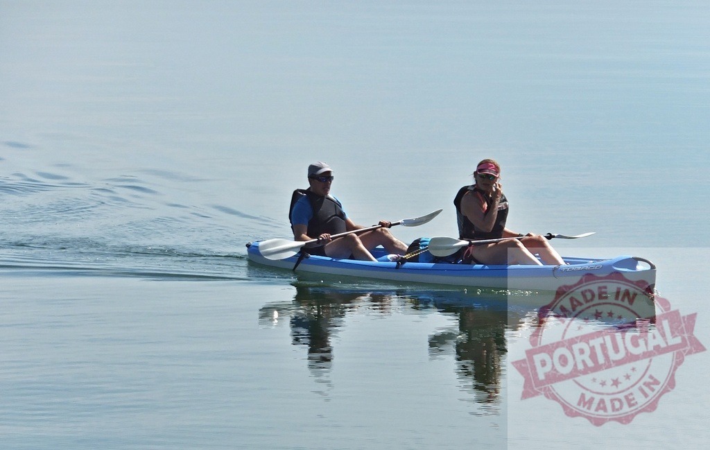 Couple paddling tandem kayak on calm lake water | Couple enjoying kayaking together on peaceful open water under clear sky - Realized with Pictrs.com