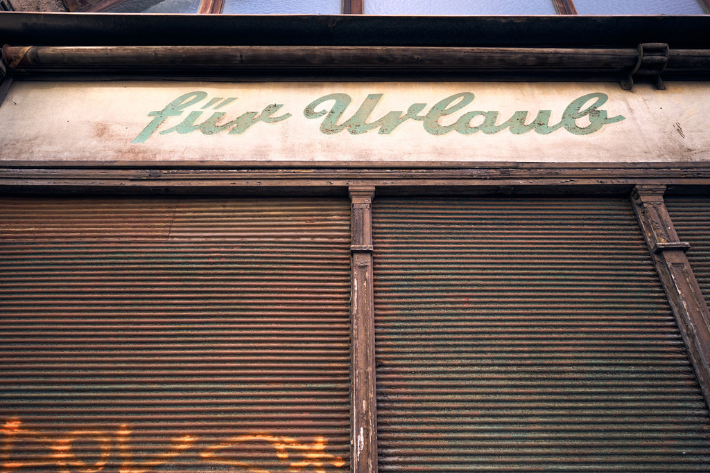 geschlossene Jalousie eines Reisebüros | Wien, Austria - March 15, 2023: Details am Wiener Gürtel; geschlossene Jalousie eines Reisebüros mit Aufschrift; für Urlaub. - Realisiert mit Pictrs.com