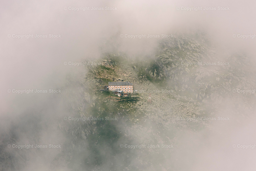 The Hut in the Clouds | A mountain hut through the clouds from a distance.  - Realisiert mit Pictrs.com