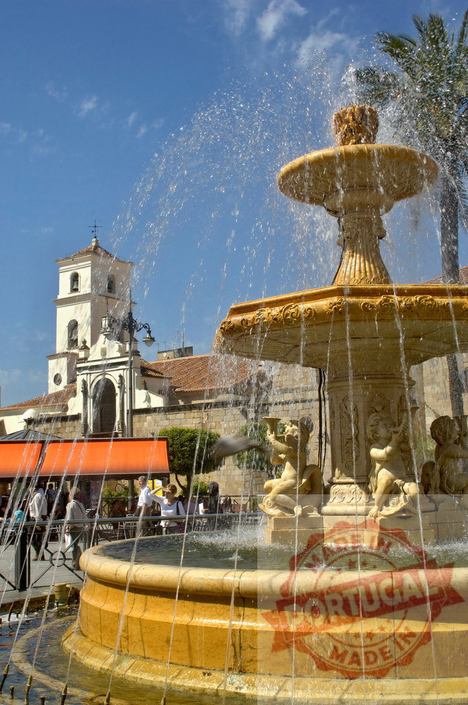 Fountain spraying water in Plaza de la Encarnación, Jerez de la Frontera, Spain. Extremdura - Spain | Ornate stone fountain spraying water in a sunny Plaza de la Encarnación against a blue sky - Realized with Pictrs.com