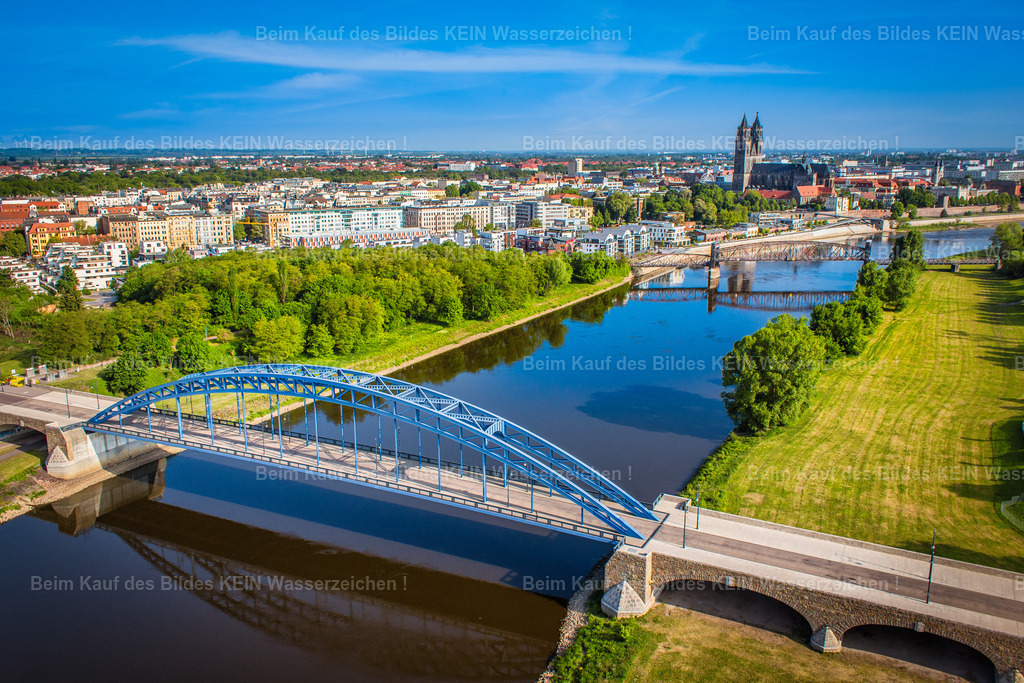 000_Sternbrücke Elbe Hubbrücke Dom in Magdeburg - Das Foto Luftbild-1980 | Diese eindrucksvolle Luftaufnahme zeigt die Sternbrücke an einem sonnigen Sommertag aus einer außergewöhnlichen Perspektive. Die Elbe nimmt den größten Teil des Bildes ein und führt den Blick bis zur Magdeburger Innenstadt. Im Hintergrund prägen die historische Hubbrücke und der Magdeburger Dom die Skyline der Landeshauptstadt. Das grüne Elbufer auf der rechten Bildseite bildet einen harmonischen Kontrast zum tiefen Blau von Wasser und Himmel und unterstreicht die besondere Lage der Sternbrücke zwischen Natur und Stadt.Dieses Motiv gehört zu den zahlreichen Brückenaufnahmen, aus denen Sie Ihren persönlichen Luftbildkalender individuell zusammenstellen können. Ob moderne Elbbrücken, historische Bauwerke oder außergewöhnliche Luftaufnahmen entlang der Elbe – Sie entscheiden selbst, welche Motive Ihren Kalender schmücken sollen. Die gezeigten Luftbilder dienen als Inspiration und können jederzeit durch andere Aufnahmen aus dem umfangreichen Luftbildarchiv ersetzt oder ergänzt werden.So entsteht ein hochwertiger Firmenkalender mit persönlichem und regionalem Bezug. Sie wählen Ihre Wunschmotive aus, ich übernehme die professionelle Gestaltung und Umsetzung. Die individuelle Motivauswahl gehört selbstverständlich zum Service und ermöglicht einen Brückenkalender, der genau Ihren Vorstellungen entspricht – ohne zusätzliche Kosten. - Realisiert mit Pictrs.com