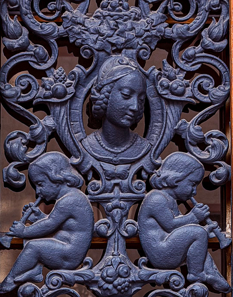Wandbild Kunstdruck Poster – Architektur Details & Geometrie: Antikes Barock-Relief von Robert Steinke | Ein meisterhaftes und zutiefst beeindruckendes Zeugnis historischer Handwerkskunst, festgehalten in einer detailreichen Architektur-Fotografie. Dieses exklusive Kunstwerk zeigt ein prachtvolles, barockes Relief aus Basel, das durch seine kunstvollen Steinmetz-Arbeiten besticht. Im Zentrum thront ein edles Frauenporträt, umrahmt von opulenten, floralen Ornamenten und zwei filigran gearbeiteten Engeln mit Posaunen. Das gezielte Spiel aus Licht und tiefen Schatten betont die feinen Steinstrukturen und verleiht dem gesamten Motiv eine atemberaubende, plastische Dreidimensionalität. Dieses ausdrucksstarke Motiv bringt eine erhabene, klassische Eleganz und eine majestätische Galerie-Atmosphäre in deine Räume. Ein absolut zeitloser und stilvoller Blickfang für ein modernes Wohnzimmer, das kreative Büro, ein helles Loft, Kanzleien oder repräsentative Geschäftsräume.Um die feinen Gravuren, die Meißelspuren und die plastische Tiefe dieses historischen Reliefs perfekt zur Geltung zu bringen, empfehle ich den Druck auf unseren Premium-Materialien: Erlebe maximale Tiefenwirkung und kinoreife Brillanz auf edlem Acrylglas, moderne Galerie-Eleganz auf robustem Alu-Dibond oder einen weichen, klassischen Charakter auf einer matten Leinwand. Hol dir dieses Stück Basler Geschichte direkt an deine Wand! - Realisiert mit Pictrs.com