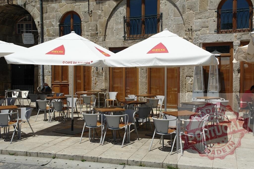 Outdoor cafe tables and umbrellas in historic Portuguese street | Outdoor cafe tables and umbrellas await customers on a sunny street in Portugal - Realisiert mit Pictrs.com