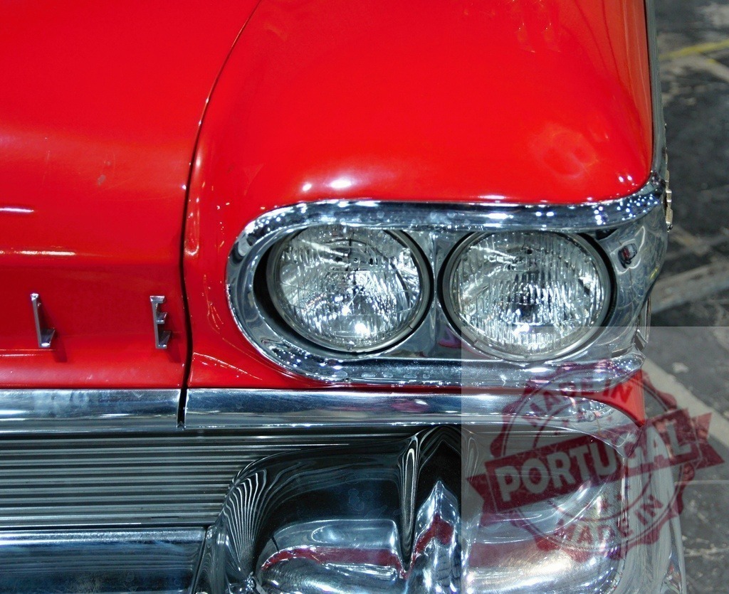 Shiny red Oldsmobile Eighty-Eight featuring prominent headlights and chrome details | Close-up of a classic red Oldsmobile car, highlighting its gleaming headlights and chrome accents - Realisiert mit Pictrs.com