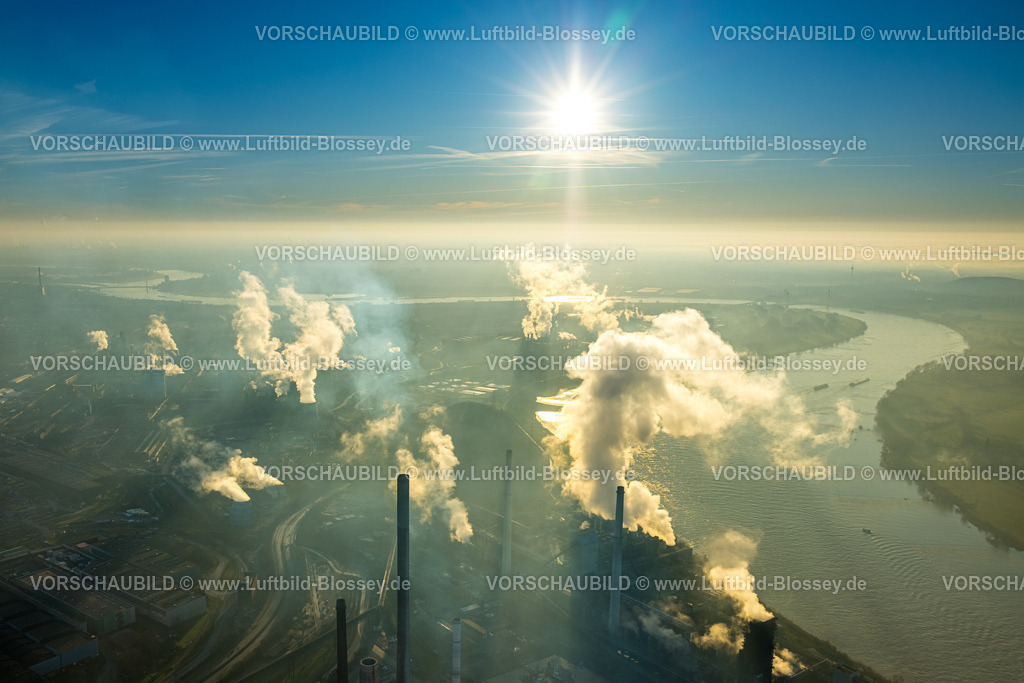 Duisburg241202910 | Luftbild, Thyssen Krupp Steel Europe AG am Fluss Rhein, Werkshafen Schwelgern, Gegenlicht und strahlenförmige Sonne am blauen Himmel, qualmende rauchende Schornsteine, Marxloh, Duisburg, Ruhrgebiet, Nordrhein-Westfalen, Deutschland