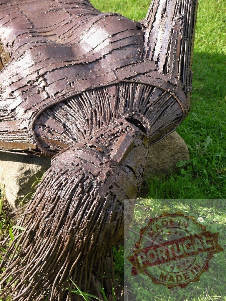 Abstract metal human form sculpture lying on grass | Textured iron sculpture depicting a human figure resting outdoors - Realized with Pictrs.com