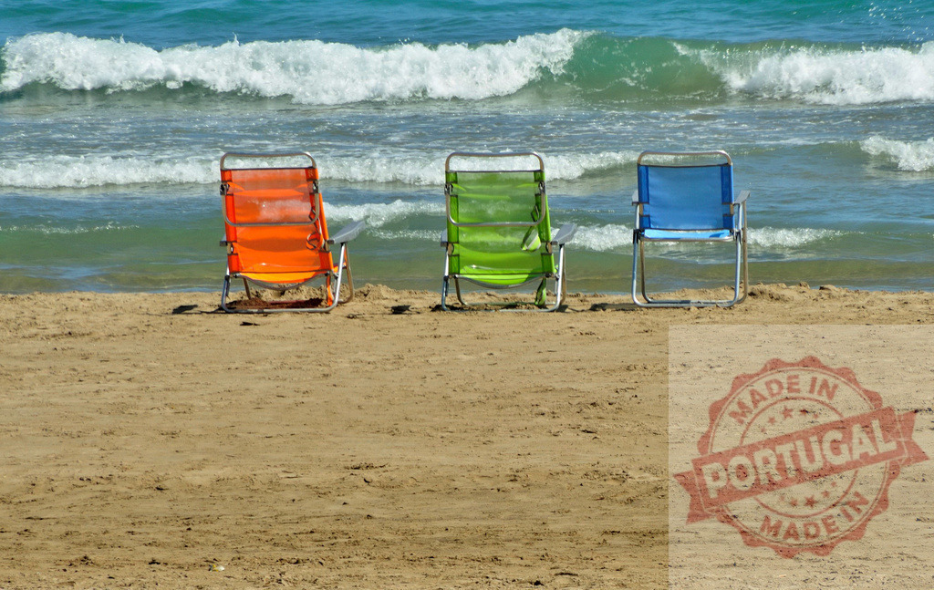 Colorful beach chairs lining sandy shore by ocean waves. Spain - Castellon | Colorful beach chairs waiting for relaxation on a sunny sandy shore next to ocean waves - Realized with Pictrs.com