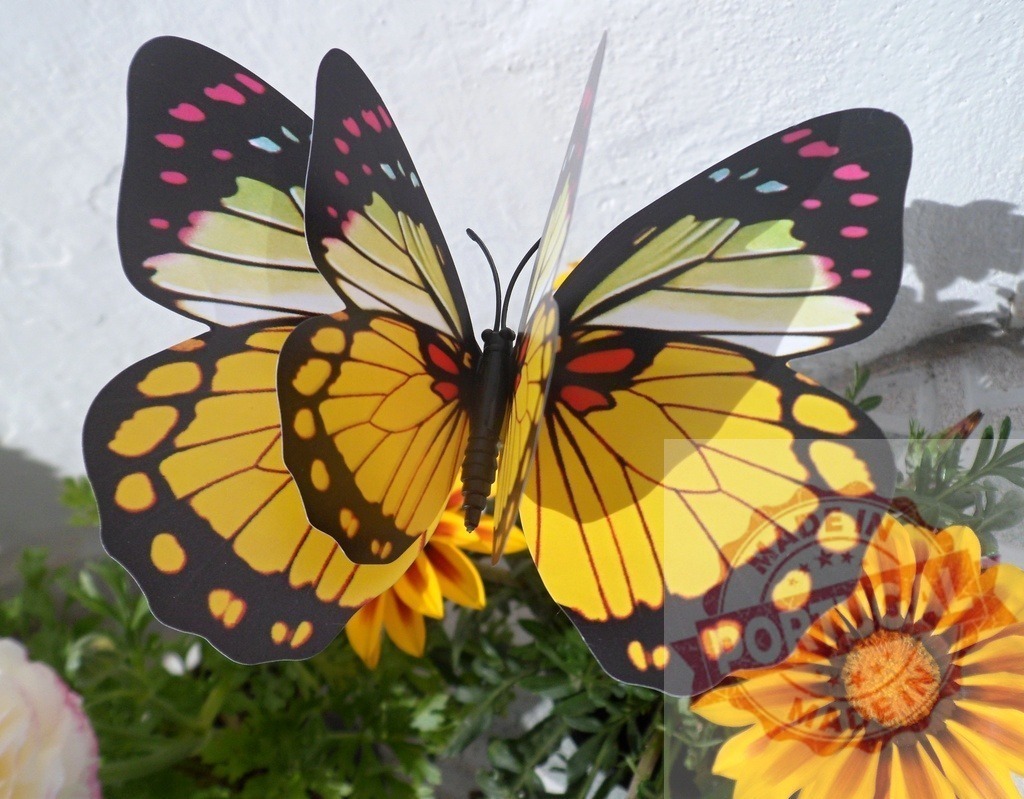 Artificial butterfly decoration in garden flower pot | Artificial yellow and black butterfly decorating a vibrant outdoor flower arrangement - Realized with Pictrs.com