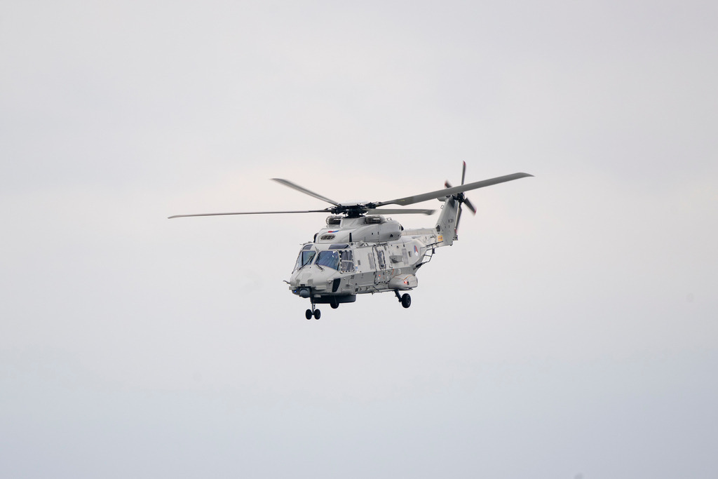 "Sealion" niederländische Marineflieger | Eine detaillierte Profilaufnahme eines grauen NH90-Transporthubschraubers der niederländischen Marine vor einem neutralen, bewölkten Himmel. Gut zu erkennen sind die Kennnummer "319", das Hoheitsabzeichen sowie technische Details wie das Fahrwerk und die Sensorik an der Nase des Luftfahrzeugs. - Realisiert mit Pictrs.com
