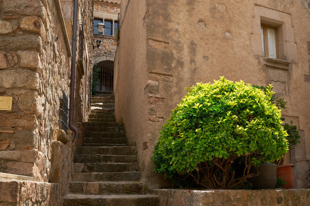Detailaufnahme in der Altstadt von Tossa de Mare | Tossa de Mare, Frankreich - May 12, 2024: Detailaufnahme in der Altstadt von Tossa de Mare; Tisch mit vier Stühlen im Schatten. - Realisiert mit Pictrs.com