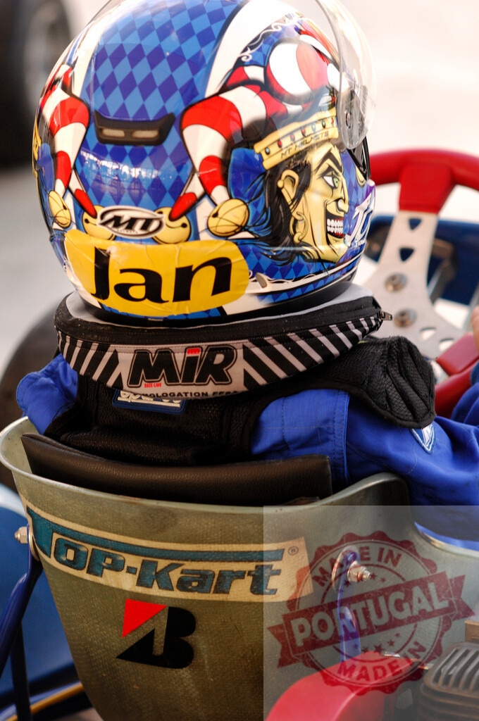 Pilot wearing colorful helmet driving go-kart on track | Karter wearing colorful helmet with jester drawing competing in go-kart race - Realisiert mit Pictrs.com