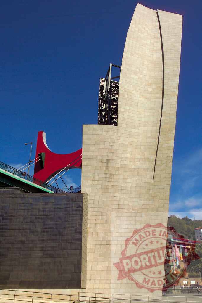 Guggenheim Museum Bilbao featuring La Salve Bridge architecture. Spain - Bilbao | Guggenheim Museum Bilbao with the red arch of La Salve Bridge against a blue sky - Realisiert mit Pictrs.com
