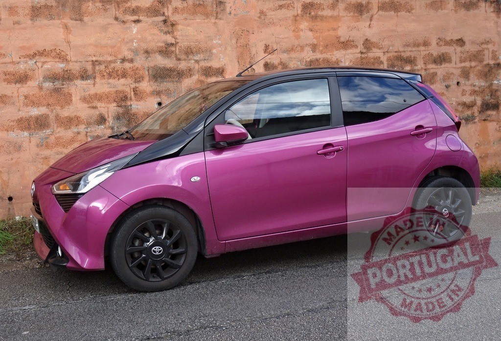 Toyota Aygo car, pink urban compact vehicle | Toyota Aygo parked outdoors, showcasing its distinctive pink color and compact design - Realized with Pictrs.com