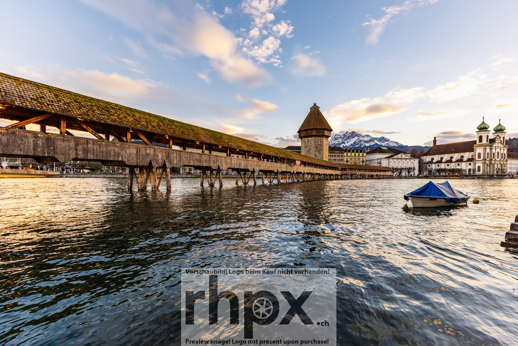 Kapellbrücke Luzern mit Pilatus | Holz. Wasser. Bergmassiv. Der Blick gleitet entlang der weltberühmten Kapellbrücke hin zum markanten Gipfel des Pilatus. Das Zusammenspiel von historischem Bauwerk und wilder Bergwelt prägt diese einzigartige Luzerner Kulisse in warmem Abendlicht. Wähle unter "Produktauswahl" dein Wunschformat: Vom klassischen Wandbild über Puzzle &amp; Tassen bis zum digitalen Download (z.B. als Handy-Hintergrund). - Realisiert mit Pictrs.com