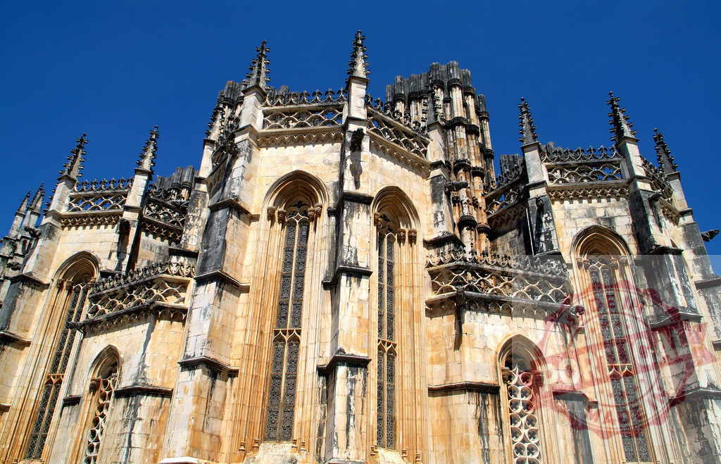 Batalha Monastery, Portugal, gothic architecture facade under blue sky | Batalha Monastery's detailed gothic architecture, a historic landmark and UNESCO World Heritage site - Realisiert mit Pictrs.com