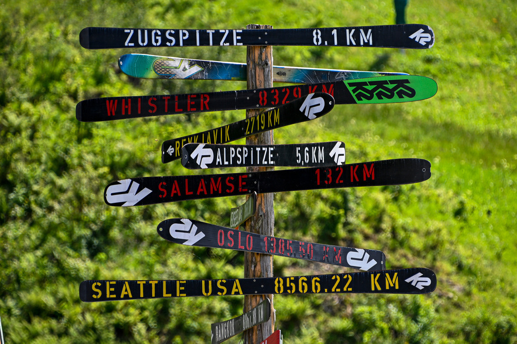 Der Kompass für Abenteurer | Ein Wegweiser der ganz besonderen Art: Aus alten Skiern gefertigt, weist dieser originelle Pfahl mitten im Grünen den Weg zu Nah- und Fernzielen – von der Zugspitze über die Alpspitze bis hin nach Oslo, Whistler oder Seattle. Das kreative Upcycling-Kunstwerk weckt auf charmante Weise Fernweh und Entdeckergeist. Es verbindet die alpine Heimat von Garmisch-Partenkirchen mit der weiten Welt und lädt Vorbeigehende zum Träumen von großen Reisen und unvergesslichen Bergabenteuern ein. - Realisiert mit Pictrs.com