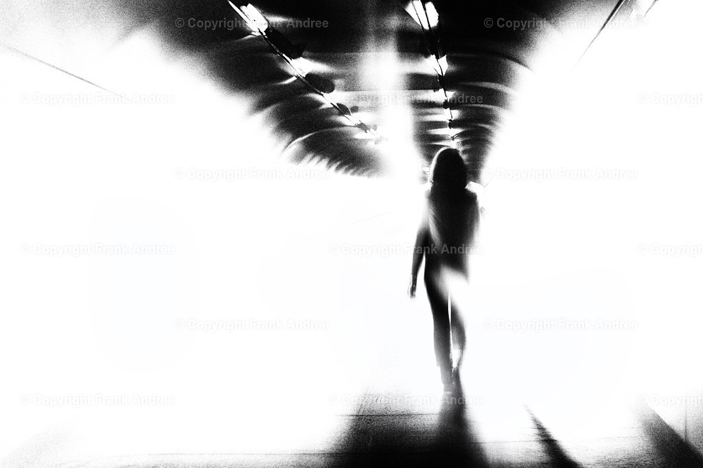 Quo Vadis 4 | Eine junge Frau geht allein durch einen lichtdurchfluteten Tunnel. Digitale Kunst in schwarz weiß. - Realisiert mit Pictrs.com