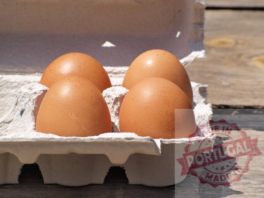 Brown eggs in carton on wooden table | Fresh brown eggs sitting in a recyclable carton on a rustic wooden surface in bright sunlight - Realized with Pictrs.com
