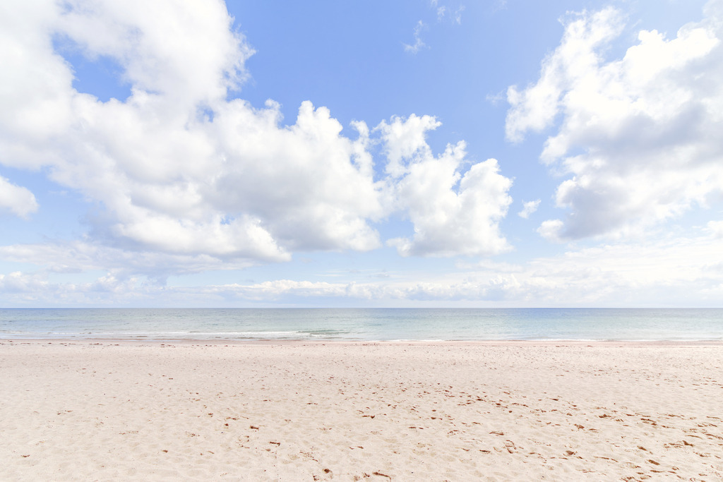 Sanfter Strandhorizont – Minimalistisches Meeresbild | Dieses minimalistische Meeresbild fängt den Strand in seiner ruhigsten Form ein: Die weite Sandfläche, das sanfte Blau des Meeres und leichte Wolkenstrukturen am Horizont strahlen pure Leichtigkeit aus. Die helle, klare Komposition schafft eine zeitlose, meditative Atmosphäre – ideal als maritimes Wandbild für Räume, die eine offene, lichtdurchflutete Eleganz ausstrahlen sollen.