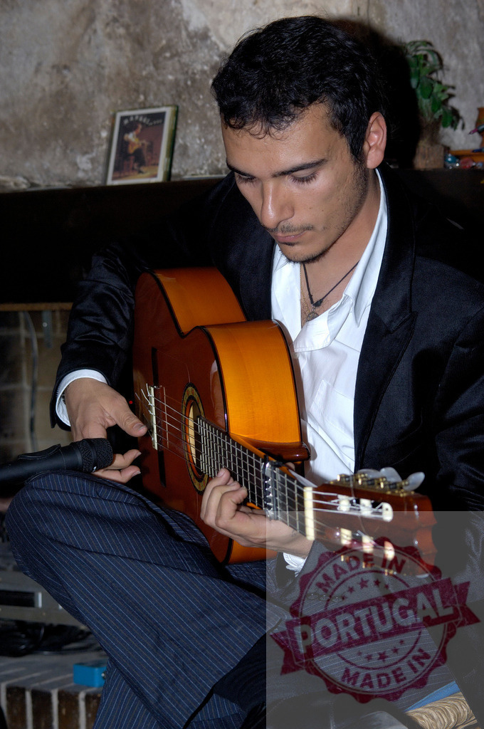 Male musician playing classical guitar during a performance | Musician playing a wooden classical guitar with focus during a live performance - Realisiert mit Pictrs.com