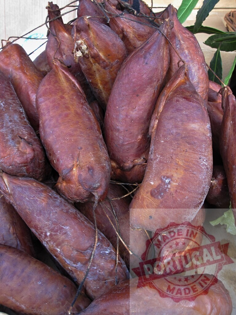Cured smoked prosciutto meat hanging at market stall | Artisanal cured smoked meat products at a traditional food market - Realized with Pictrs.com