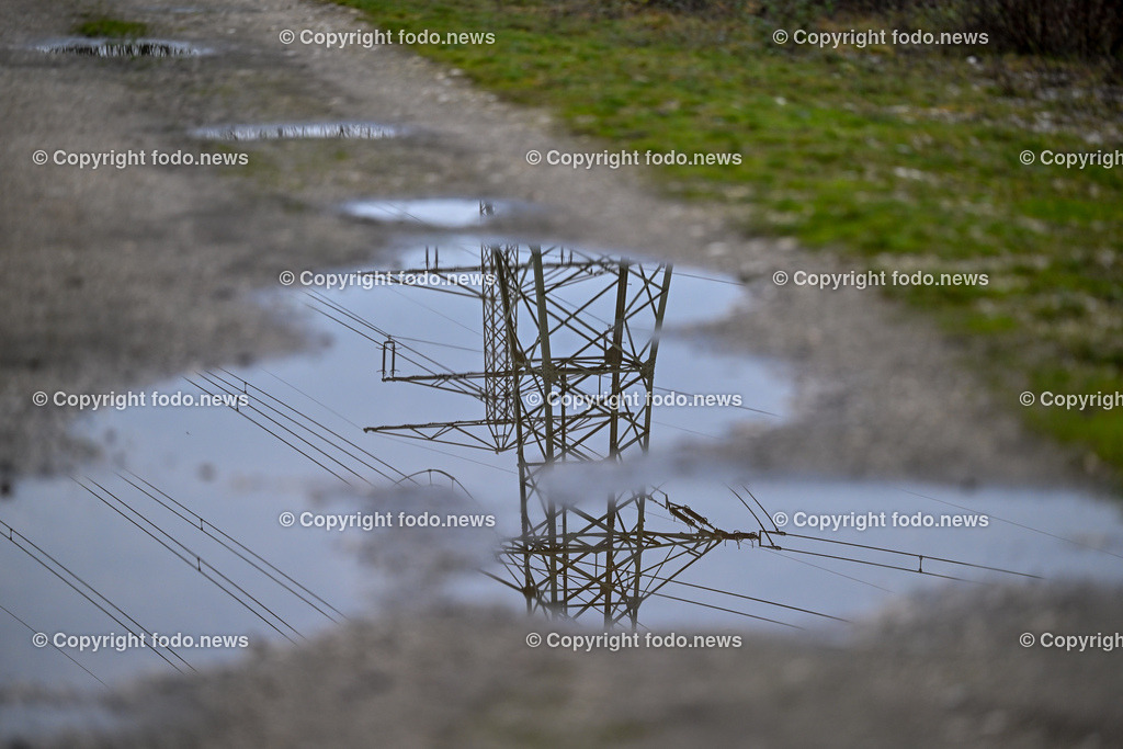 Stromleitung_ 11.12.2024-3 | 11.12.2024, Linz, AUT, Strom, im Bild Themenbild, Strommast, Stromleitung, Stromleitungen, Strom, Stromausfall, Hochspannung, Black Out, Power, Energy, Spiegelung, Pfuetze, Wasser, Symbolbild, Feature