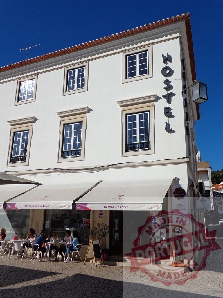 Ruby cafeteria and hostel building in Portugal | People enjoying outdoor seating at the Ruby cafe with the hostel upstairs under a clear sky - Realisiert mit Pictrs.com