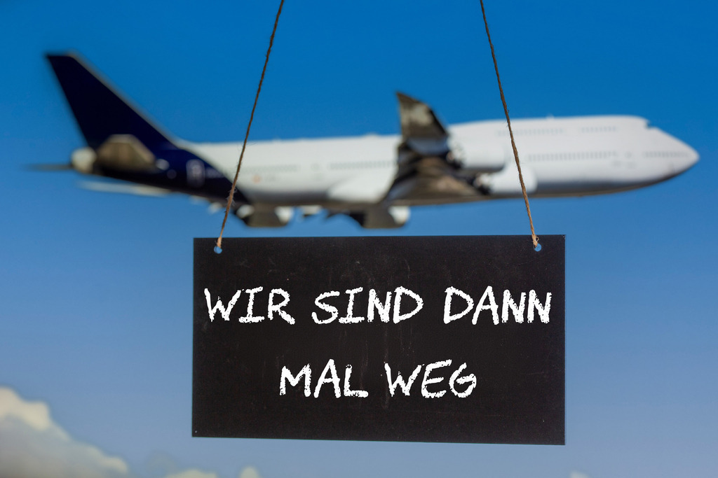Symbolbild Betriebsferien: Schild mit der Aufschrift WIR SIND DANN MAL WEG vor einem startenden Flugzeug (Composing) | Symbolbild Betriebsferien: Schild mit der Aufschrift WIR SIND DANN MAL WEG vor einem startenden Flugzeug (Composing) - Realisiert mit Pictrs.com