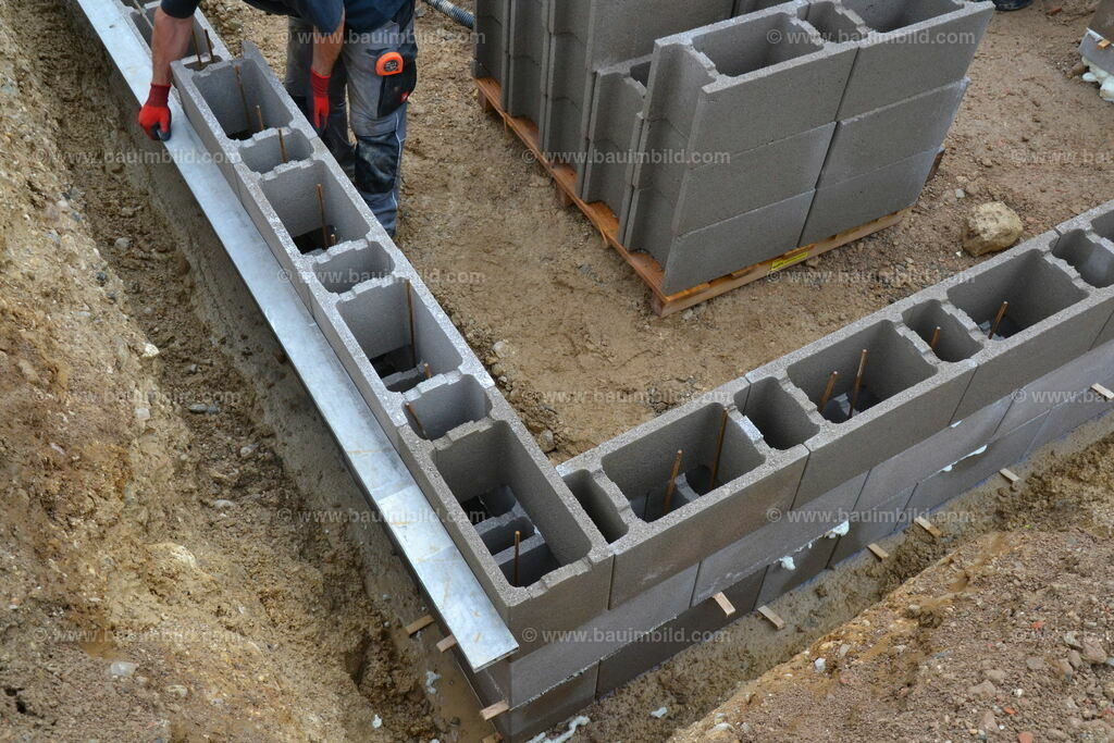 Ecke Schalsteinmauer | Arbeiter beim Ausrichten von Mauerwerk mit Ecke aus Schalungssteinen