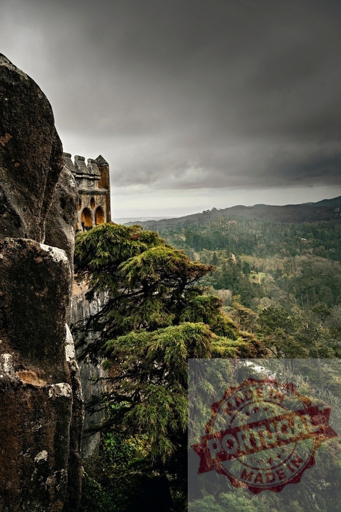 Pena Palace castle tower on cliff Portugal | Pena Palace tower peeking over a rocky cliff with a dense forest landscape under a cloudy sky - Realized with Pictrs.com