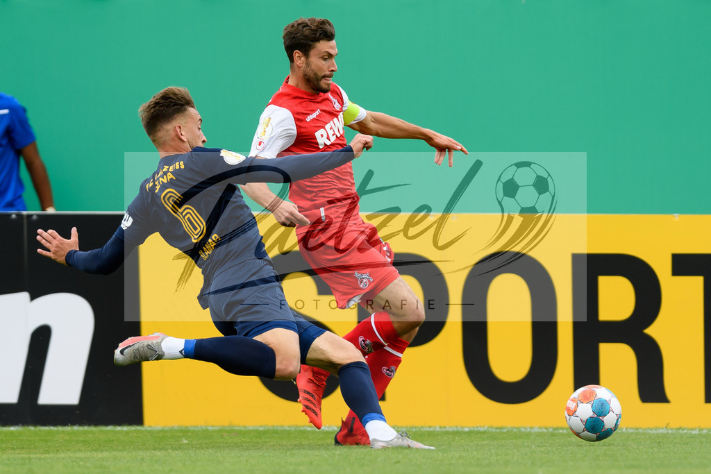 JENKOE20210808_029 | Fussball, Herren: Dennis Slamar (FC Carl Zeiss Jena) und Jonas Hector (1. FC Koeln) im Zweikampf beim Spiel der 1. Runde im DFB-Pokal zwischen FC Carl Zeiss Jena und 1. FC Koeln im Ernst-Abbe-Sportfeld am 08.08.2021 in Jena, Deutschland.DFB / DFL REGULATIONS PROHIBIT ANY USE OF PHOTOGRAPHS AS IMAGE SEQUENCES AND/OR QUASI-VIDEO. - Realisiert mit Pictrs.com