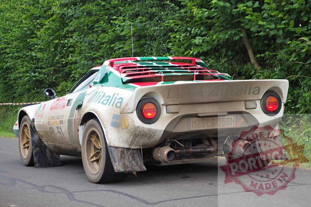 Lancia Stratos rally car racing on circuit | Lancia Stratos vintage rally car driving on asphalt in forest, showing rear detail - Realisiert mit Pictrs.com