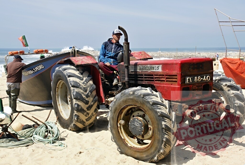 Fisherman driving tractor pulling fishing boat on beach | Fishermen on a sandy beach preparing a traditional fishing boat for launching into the ocean - Realized with Pictrs.com