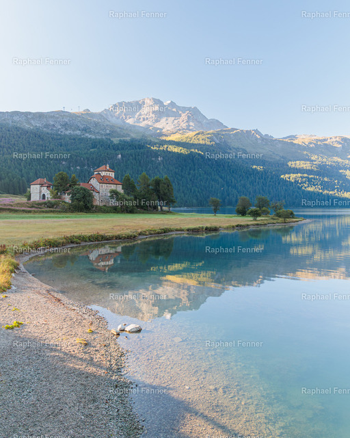 Morgenstimmung am Silvaplanersee | Die ersten Sonnenstrahlen des Tages tauchen die Uferlandschaft am Silvaplanersee im Oberengadin in ein warmes Licht. Das ruhige Wasser spiegelt die umliegenden Berge und schafft eine friedliche Atmosphäre, die die Schönheit der Engadiner Natur eindrucksvoll einfängt.