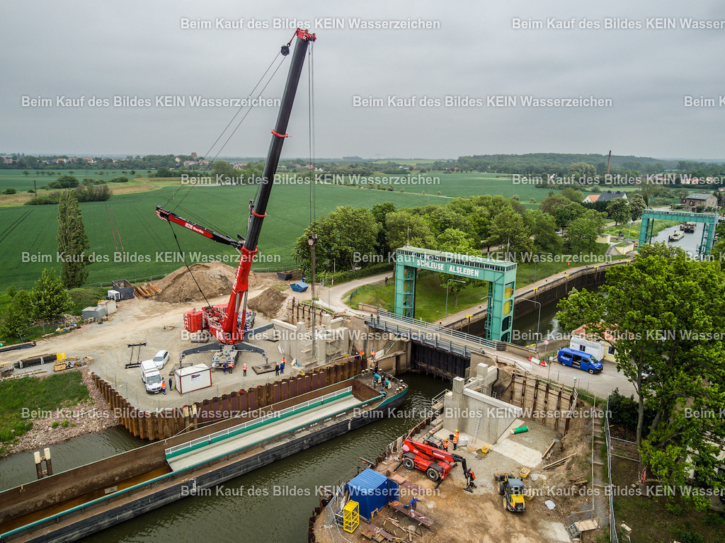Schleuse_Alsleben_Foto_Lehmann-3 | Die Drohnenaufnahme zeigt ein Schiff mit dem Brückenteil auf dem Weg zur Schleuse Alsleben. Das Bauteil wird für den Einbau der neuen Brücke zur Baustelle transportiert. Die fotografische Begleitung dieses besonderen Bauabschnitts erforderte eine genaue Abstimmung des Drohnenflugs auf den zeitlichen Ablauf der Arbeiten. Entscheidend war, den richtigen Zeitpunkt zu treffen, da das Brückenteil nur während eines begrenzten Zeitfensters mit dem Kran vom Schiff auf die Baustelle gehoben werden konnte.Die Aufnahme ist Teil des Mitteldeutschen Bildarchivs von Luftbildfotograf Steffen Lehmann. - Realisiert mit Pictrs.com