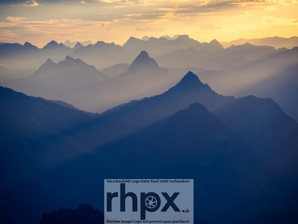 Lichtdurchflutete Gipfel | Licht. Weite. Magie.Dramatische Sonnenstrahlen durchbrechen die Wolkendecke und tauchen die gestaffelten Bergketten in ein atmosphärisches, goldenes Licht. Dieser Moment fängt die pure Erhabenheit der Alpen in einer einzigartigen Lichtstimmung ein.Wähle unter "Produktauswahl" dein Wunschformat: Vom klassischen Wandbild über Puzzle &amp; Tassen bis zum digitalen Download (z.B. als Handy-Hintergrund). - Realisiert mit Pictrs.com