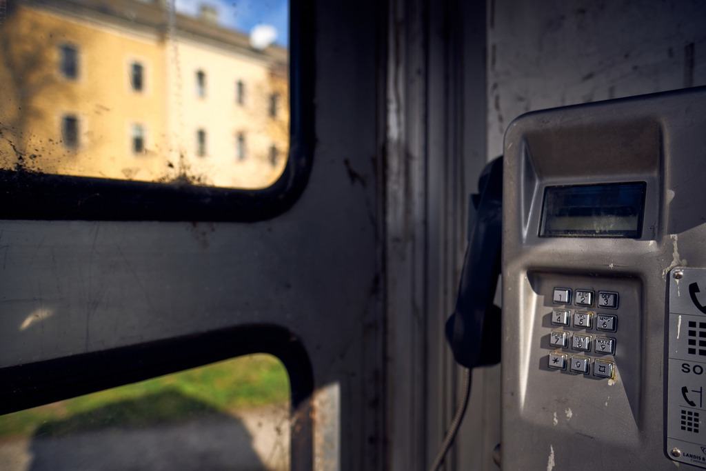 Alte Telefonzelle mit Münztelefon vor einer Wohnanlage | Wien, Austria - March 17, 2021: Alte schmutzige Telefonzelle mit Münztelefon vor einer Wohnanlage. - Realisiert mit Pictrs.com