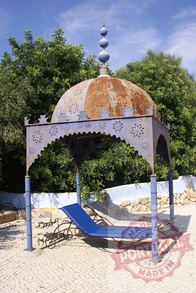 Ornately decorated outdoor gazebo with rustic dome and lounge chairs | Ornate metal gazebo with a rusted dome providing shade for two sun loungers on a patio - Realized with Pictrs.com